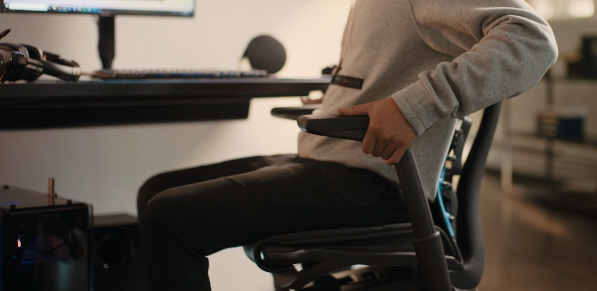 책상 앞의 사람에 의해 조정되는 검은색 Embody Gaming Chair 팔걸이의 클로즈업 동영상.